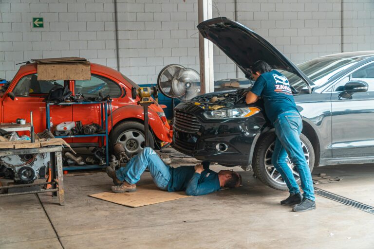 Mechanics working in an automotive workshop, repairing cars and performing maintenance.